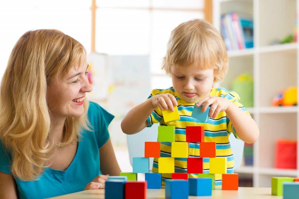 Child boy together with mother playing educational toys