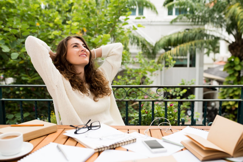 Female writer resting at her workplace with hands behind her head