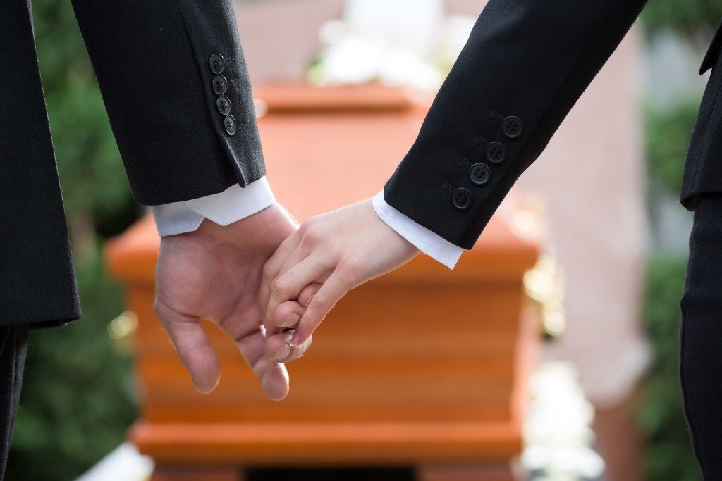 two people holding hands while in a funeral