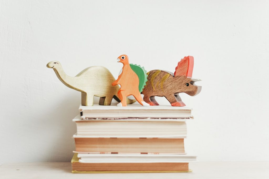 wooden dinosaurs on top of children's books