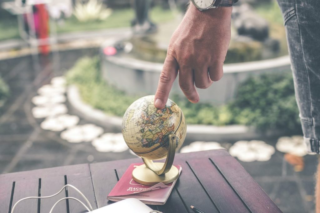 man touching globe with index finger