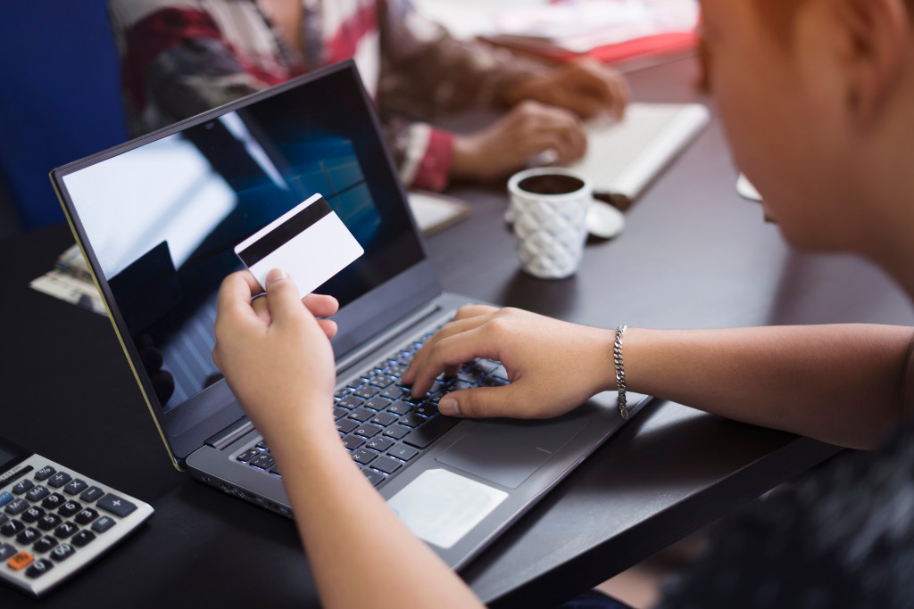 man looking at card while typing in laptop