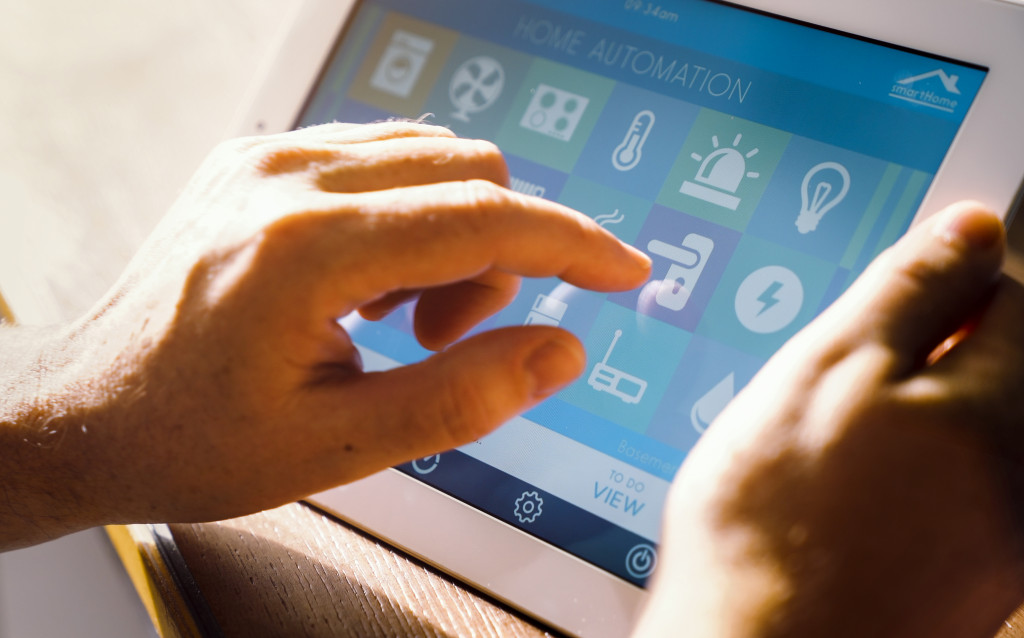 touching a smart tablet's screen which is displaying options for home automation