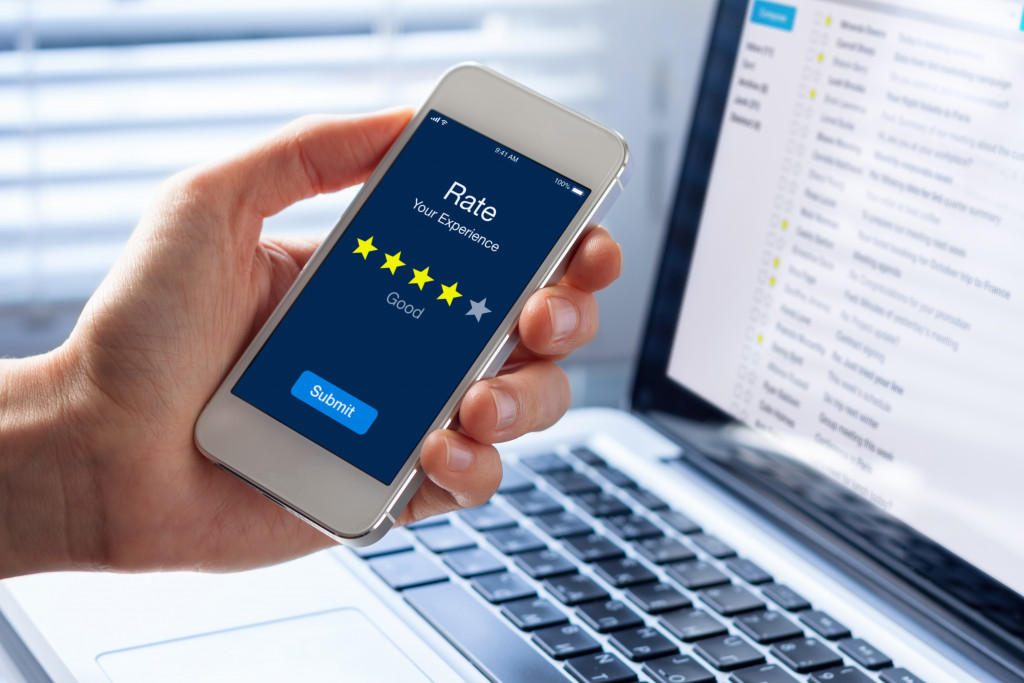 a man holding a phone in a feedback page with 4 star rate