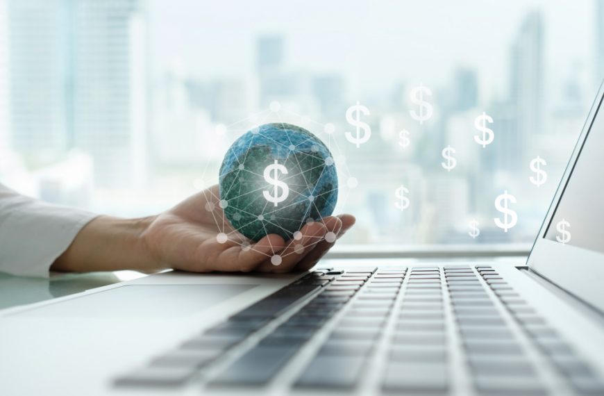 digital economy and income online concept. global on hand with network revenue dollar money icon and laptop computer.