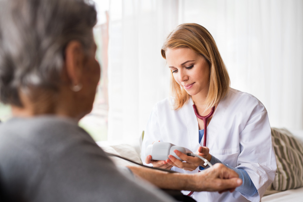 A caregiver is checking the older woman’s vital signs.