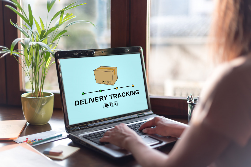 A woman is seen checking her delivery parcel on her laptop.